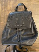 Front view of black leather Zara backpack showing embossed animal face flap with stud details and textured leather body.
