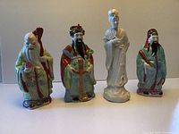 Full view of the four Asian porcelain figures arranged in a row on a flat surface against a plain background.