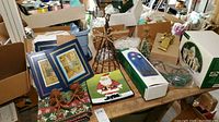 Overview of table showing Christmas decorations including tree, Santa dish, Department 56 village accessories, framed prints, and other items.