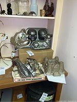 Photo showing four food molding pans on a shelf including a fish, skull, lamb and castle shape