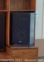 Left speaker showing wood veneer cabinet and black fabric grille with Kenwood badge at bottom.