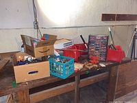 Overview of workbench with multiple storage bins, cardboard boxes containing hand tools and hardware items.