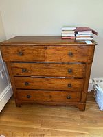 Front view of the vintage wooden dresser showing four drawers and metal knobs, scratches and scuffs visible.