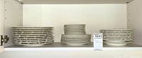 Shelf display showing stacks of white Wedgwood Queensware plates of different sizes arranged in three stacks