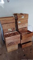 Stack of 18 wooden wine crates with various printed winery names and markings.