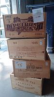 Stack of four wooden wine crates with winery logos including Petrus, Lynch Bages, Chateau Sion Haut Brion, Chateau Le Gay