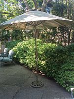 Full view of open beige canopy with base on patio