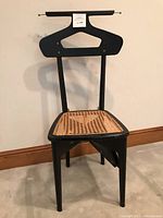 Full view of black Italian butler chair showing wooden frame, cane seat damaged and unique hanger-style backrest