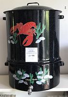 Full view of the stacked lobster boil pot with lid and clam steamer base with spigot, decorated with lobster and clam paintings.