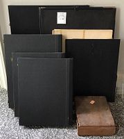 Front view of the stacked hard-sided cases and portfolios in black covers of different sizes