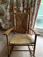 Front view of solid wood rocking chair showing woven seat and back.