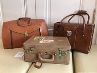 All three bags arranged together on a beige surface showing size and color differences