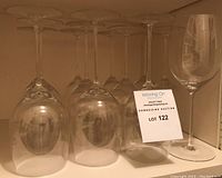 Twelve Riedel crystal wine glasses, some inverted, on shelf