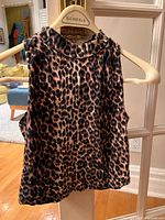 Front view of Bozzolo leopard print sleeveless top hanging on a hanger, showing high neckline and pattern detail.