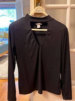 Front view of a black long-sleeve v-neck top on hanger, size medium.