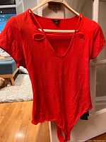 Front view of red fitted women's top bodysuit with neckline cutouts and short sleeves