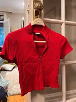 Full front view of the red ribbed knit 3/4 crop zip top with short sleeves on a hanger.