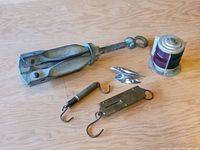 Photo showing all items including folded anchor, scales, cleat, and fishing line spool.