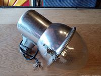 Metal street lamp head with silver finish, clear textured glass globe, attached electrical cord and bulb socket visible.