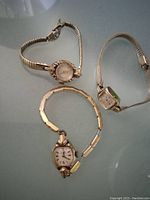 Three vintage ladies watches laying flat on a surface showing size and styles.