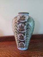 Front view of the large hand thrown pottery vase showing floral and leaf decorative patterns.