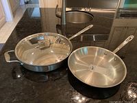 Two stainless steel pans (skillet and sauté pan with lid) on countertop