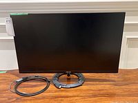 Front view of Asus gaming monitor with HDMI to USB-C Thunderbolt adapter cable coiled beside it on a wooden surface.