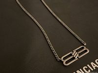 Silver-tone chain necklace with double B logo pendant displayed on black nylon Balenciaga bag background