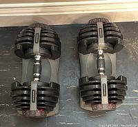 Top view of both dumbbells seated in their stands, all weight plates attached, selector dials visible