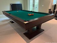 Angled front view showing full table, green felt, balls racked and single loose cue ball