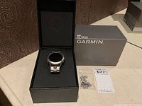 Watch in open black presentation box with Garmin grey outer box, extra links in plastic bag, MaxSold tag.