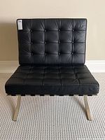 Front view of black leather tufted Barcelona style chair with stainless steel X-frame