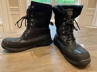 Front and side view of black lace-up UGG boots on wood surface