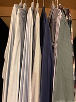 View of nine dress shirts hanging on hangers in closet showing overall lot