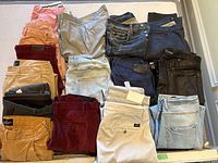 Top-down view of all 16 folded pants arranged in a 4×4 grid on bed