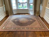 Overall view of the carpet laid on hardwood floor beneath bay window