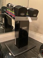 Front view of adjustable dumbbells seated on metal stand