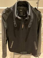 Front view of jacket hanging, showing zip front, pockets, buckle collar