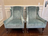 Front view of both chairs showing seat cushions, wingback sides and caster wheels