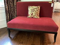 Front view of red velvet settee with one accent pillow on seat