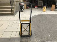 Front view of a yellow steel hand truck dolly with black handle and two wheels.