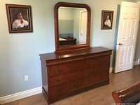 Front view of the dresser with attached mirror and nine drawers, showing the wood finish and brass handles.