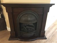 Front view of dark wood cabinet with decorative metal fireplace insert