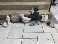 Wide view of all garden ornaments arranged on patio stairs showing bird, cat, turtle, small birds, welcome plaque, and other decorative items.
