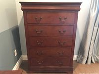 Front view of highboy chest of drawers in cherry finish showing five drawers and metal handles.