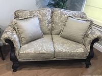 Front view of the loveseat with cream and beige striped fringe pillows