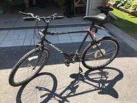 Full side view of the black Huffy mountain bike outdoor on pavement, showing overall frame and tires.