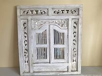 Front view of a white painted rustic wood framed mirror with two small arched hinged doors.