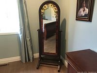 Front view showing wood frame and floral stained glass pattern on top of cheval mirror.