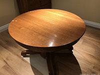 Round oak dining table top in closed position with a visible seam where inserts can be added.